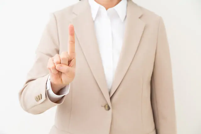 人差し指を立てるスーツ姿の女性